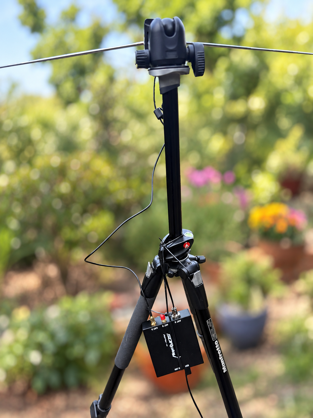 V dipole and SDR mounted on a camera tripod, with a softened garden background